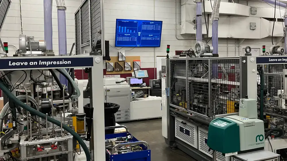 Manufacturing digital signage from Reach Media Network featured on the wall of production floor, displaying metrics.