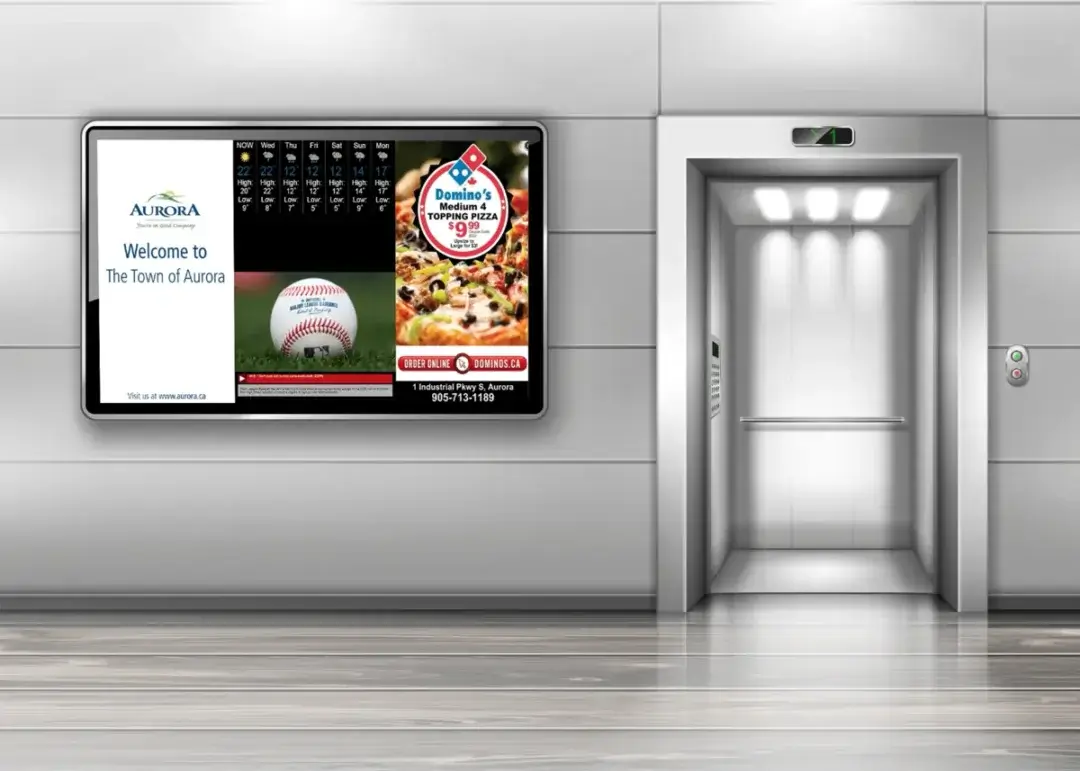 Large digital signage screen from Reach Media Network displaying Aurora Canada local deals, weather, and welcome message.